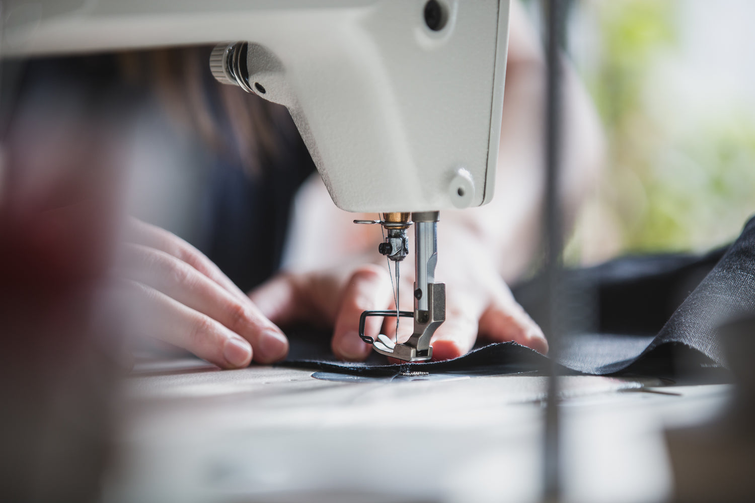 Hands feeding fabric into industrial sewing machine