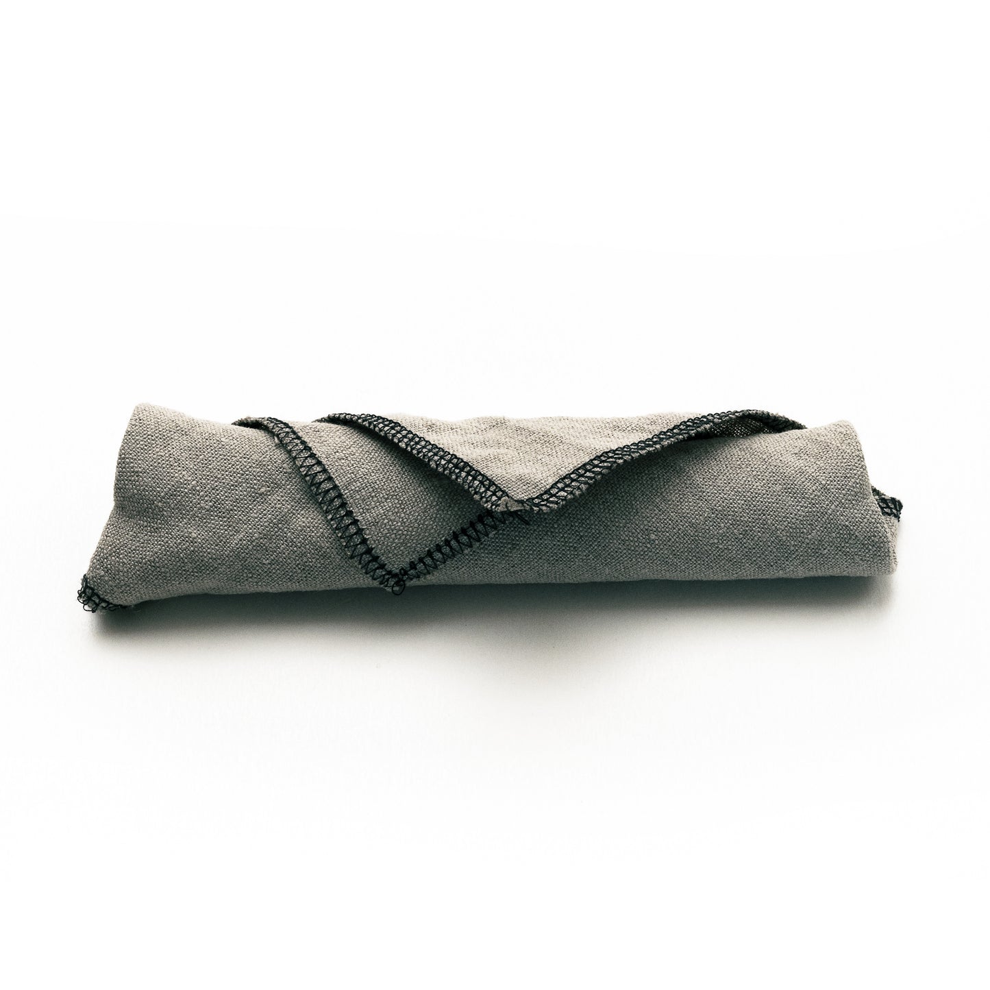 A rolled up No.9 linen applicator cloth with black sewn edges on a white background.