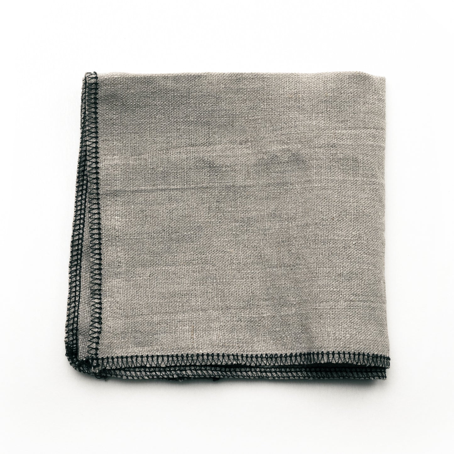 A folded No.9 linen applicator cloth with black sewn edges on a white background.