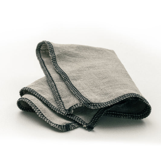 A folded No.9 linen applicator cloth with black sewn edges on a white background.